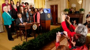 Obama Signing an Executive Order with Women Legislators Standing Behind Him